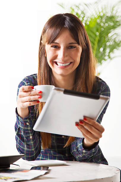 istock Smiling young woman with coffee and subject a tablet 467291469