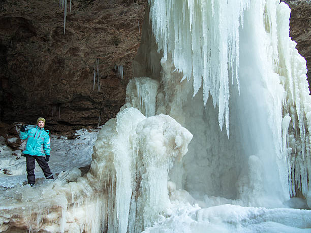 istock Boy with icicle stands by the waterfall 467292005