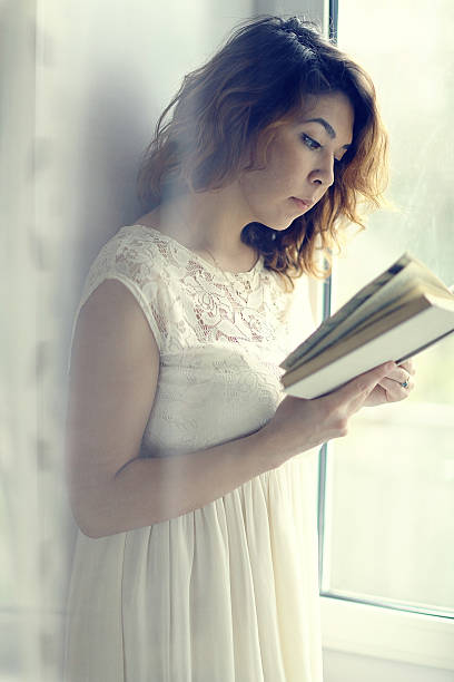istock girl reading at the window 467295078