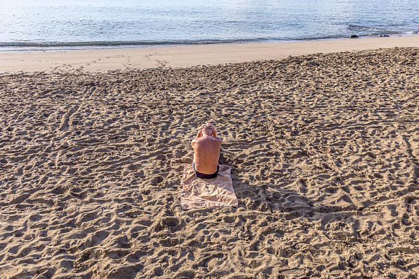 istock elderly man sitting at the beach 467298338