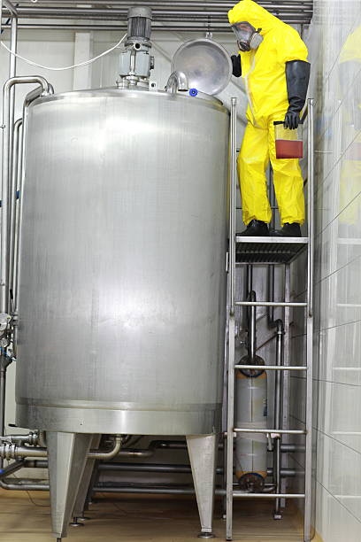 Technician in protective overall at large industrial process tank Technician in protective overall checking large industrial process tank in factory mixing vat stock pictures, royalty-free photos & images