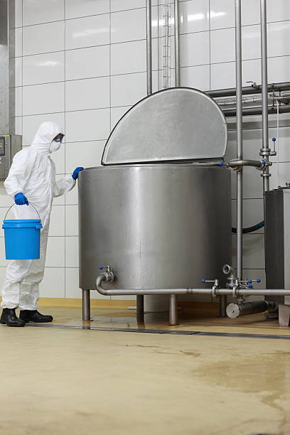 worker with  basket at large industrial process tank in factory technician in white protective overalls,mask,goggles,gloves with blue basket at large industrial process tank in factory mixing vat stock pictures, royalty-free photos & images