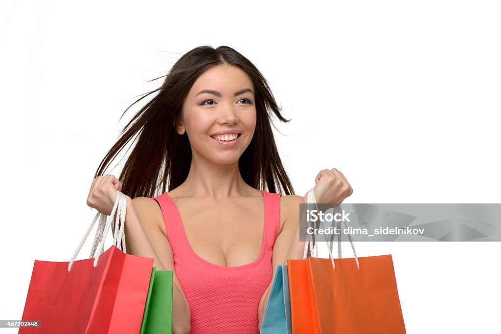 Asian smiling young woman after shopping with bags Asian smiling young woman with colorful paper bags. Concept for shop sales. Isolated on white background 2015 Stock Photo