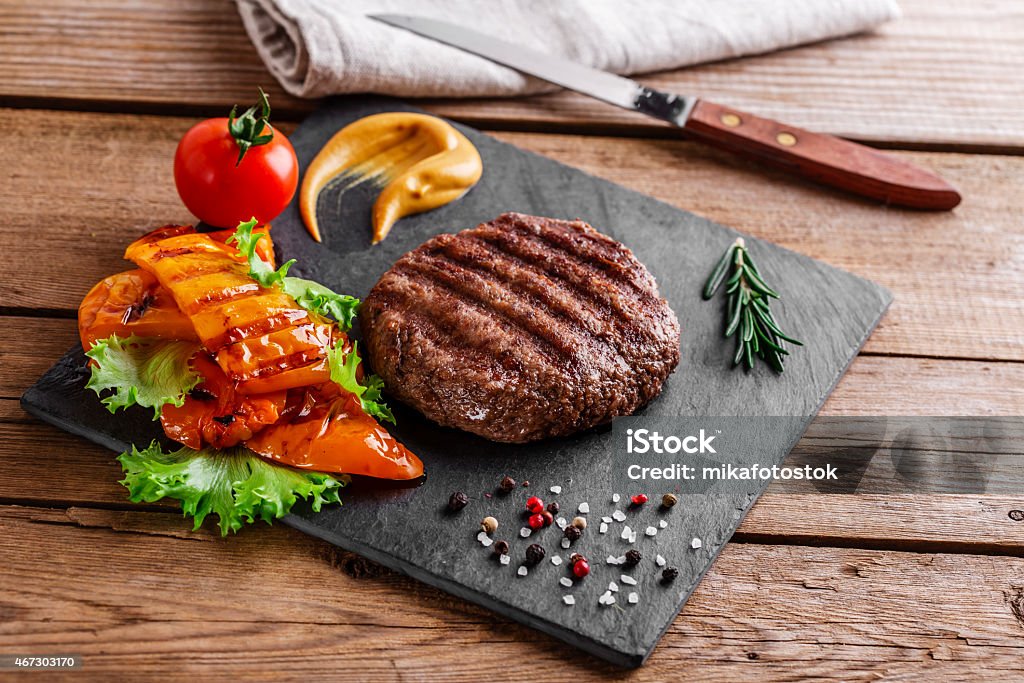 burger grill with vegetables and sauce on a wooden surface burger grill 2015 Stock Photo