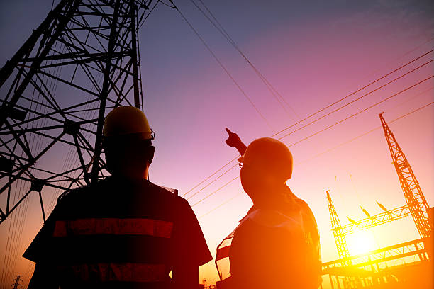 two worker watching the power tower and substation two worker watching the power tower and substation with sunset background power plant workers stock pictures, royalty-free photos & images