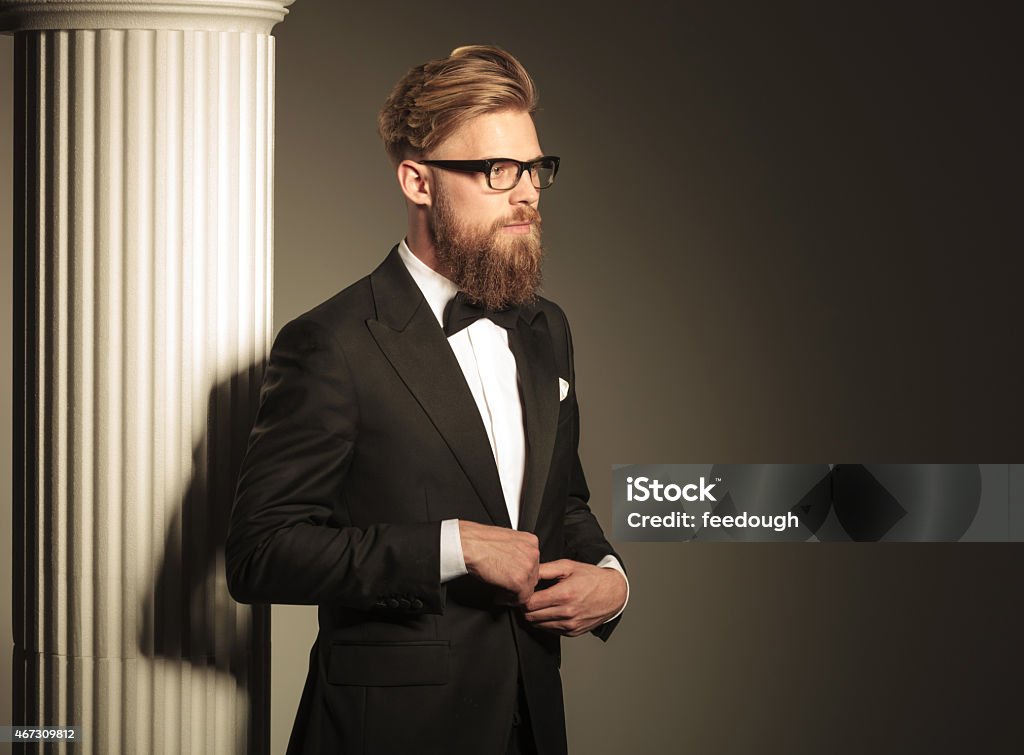 elegant business man closing his jacket. Side view of a young elegant business man looking away from the camera while closing his jacket. 2015 Stock Photo