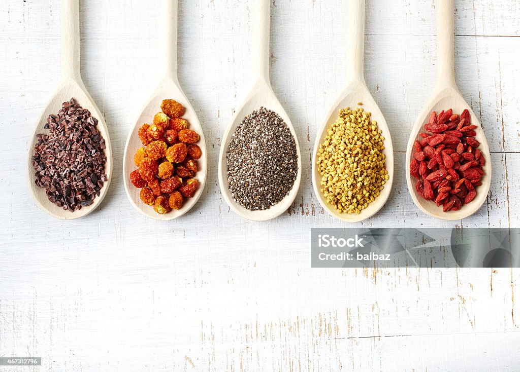 Superfoods Wooden spoons of various superfoods on white wooden background Antioxidant Stock Photo