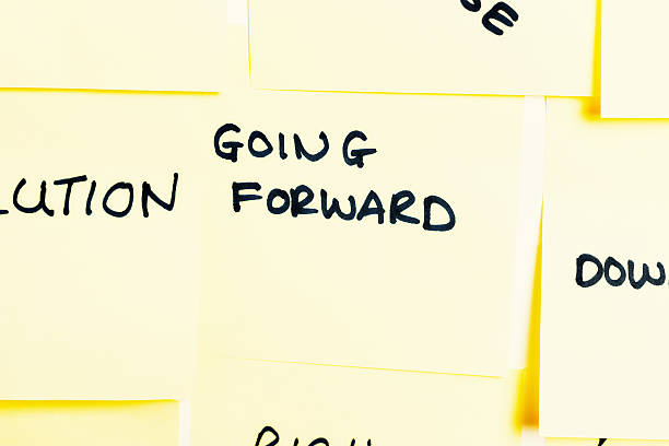 istock 'Going forward' written on  label among many pinned to noticeboard 467316921