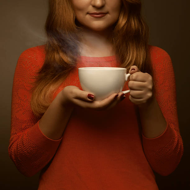 istock woman holding hot cup and smiles 467317133