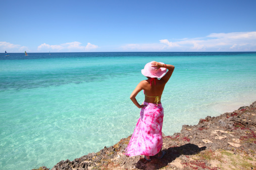 Young woman standing on the beach and looking at beautiful turquoise ocean on the Cuban beach in Varadero. See more Cuban images in my profile.