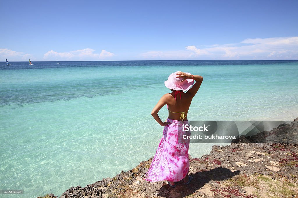 Vacation in Cuba - Young woman looking at ocean Young woman standing on the beach and looking at beautiful turquoise ocean on the Cuban beach in Varadero. See more Cuban images in my profile. Beach Stock Photo