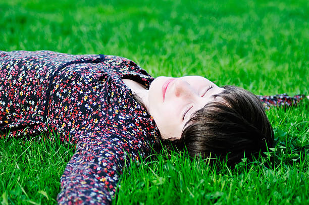 istock Happy young woman lying on green grass 467318545