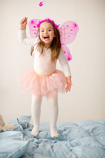jeune fille en costume de fée sauter sur le lit. - fairy costume photos et images de collection
