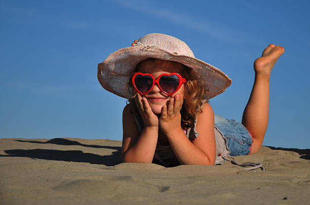 bela menina deitada em uma praia de areia - little girls fun lifestyle handcarves imagens e fotografias de stock