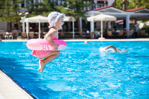Little girl jumping to the swimming pool