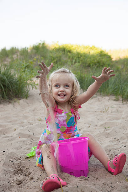 Laughing Blue Eyed Girl Looking up at camera on beach stock photo