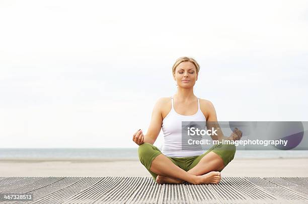 Beautiful Young Woman Sitting In Yoga Lotus Pose At Beach Stock Photo - Download Image Now