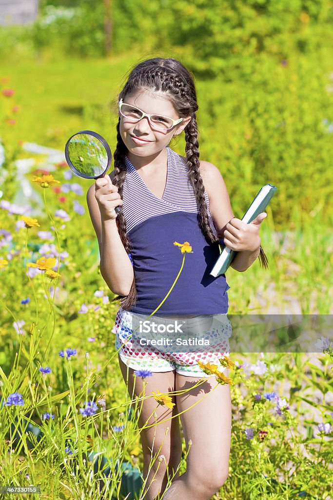 Menina com uma lupa e livro permanece entre Flores - Royalty-free 8-9 Anos Foto de stock