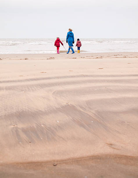istock woman and two small children on winter beach 467337617