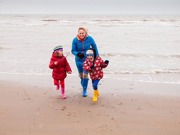 istock woman and two small children playing on winter beach 467337619