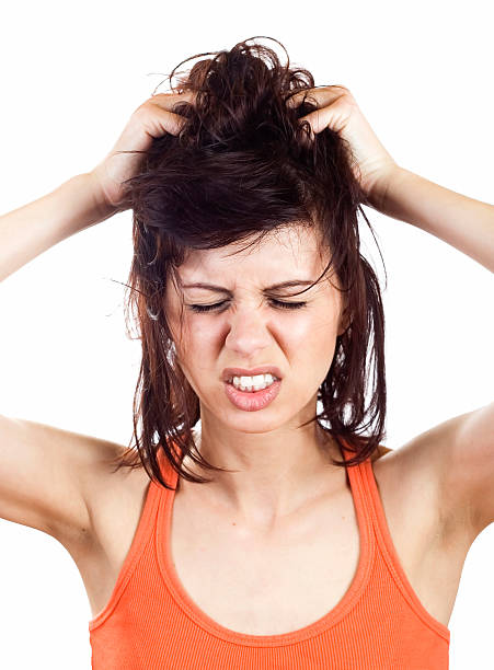 Young woman itching her scalp and grimacing http://i1364.photobucket.com/albums/r725/hofi99/UJBANNER2/andrea_banner_zps2cf1a621.jpg photography healthcare and medicine studio shot vertical stock pictures, royalty-free photos & images