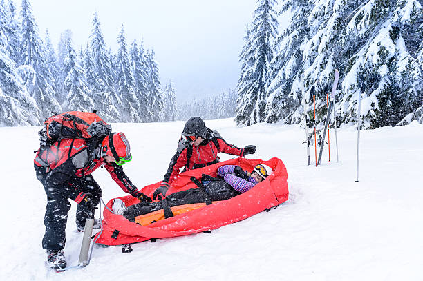 Rescue of injured woman by ski patrol sled on snowy mountain stock photo