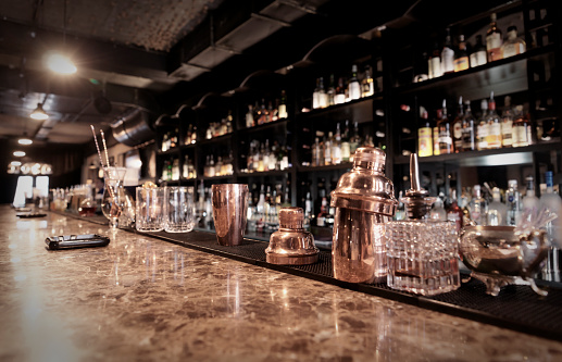 Classic bar counter with bottles in blurred background, toned image
