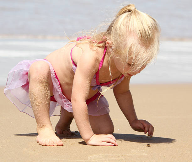 istock Little girl looking at a crab on the beach 467341916