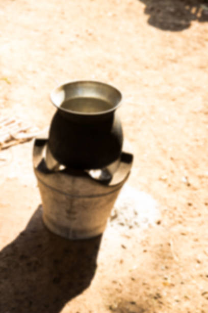 A large aluminum saucepan with two handles stands on a kitchen table against the wall of a house in an apartment