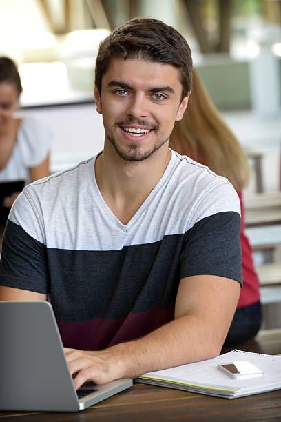 istock Male student using laptop with two others in the background 467346446