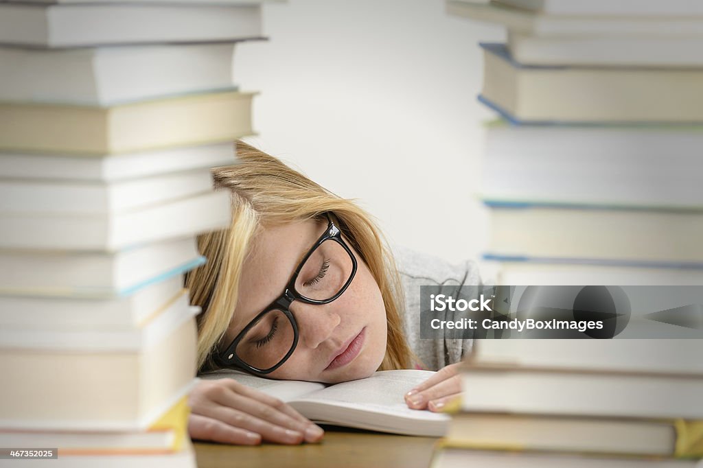 Student girl sleeping between pile of books Student girl sleeping on desk between stacks of books Adolescence Stock Photo