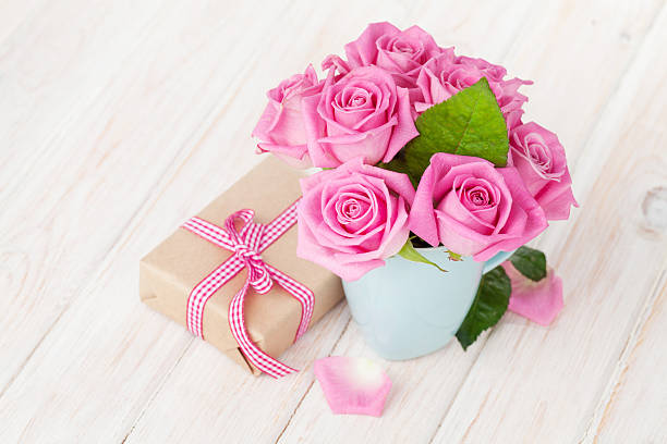 Valentines day pink roses bouquet and gift box on white wooden table