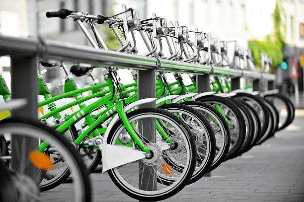 Urban scene with green bicycles for rent in a velo station