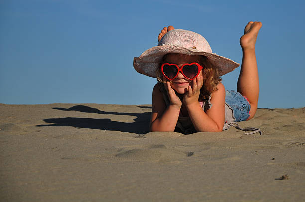 bela menina deitada em uma praia de areia - little girls fun lifestyle handcarves imagens e fotografias de stock