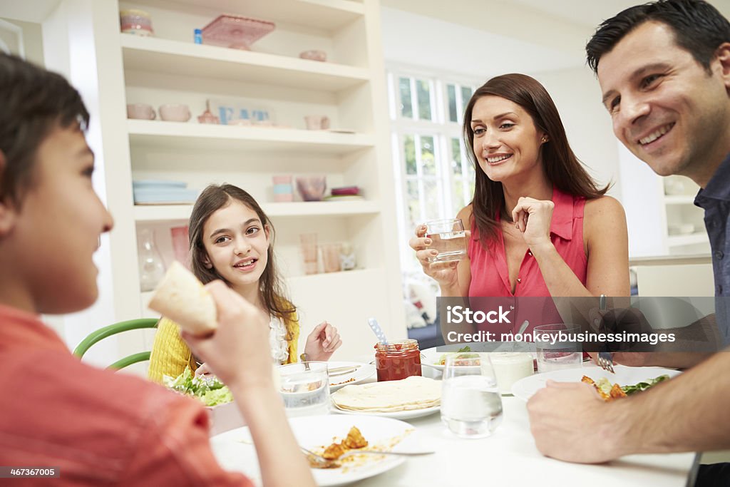Hispanic Family Sitting At Table Eating Meal Together Happy Smiling Hispanic Family Sitting At Table Eating Meal Together Eating Stock Photo