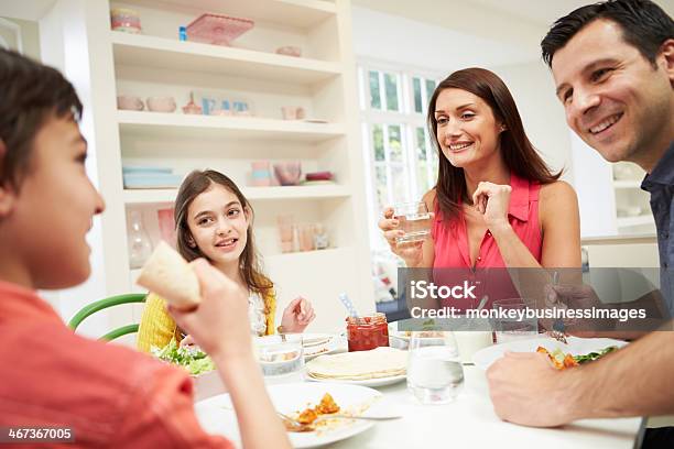Hispanic Family Sitting At Table Eating Meal Together Stock Photo - Download Image Now