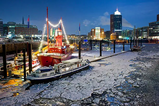 Hamburg harbor with an illuminated lightship in winter. River Elbe is frozen. 