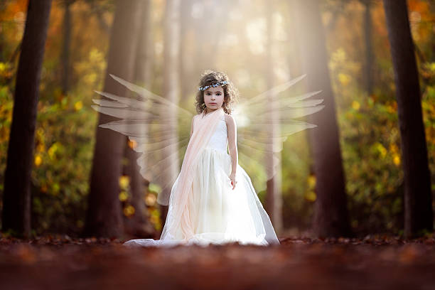 Little girl in the forest dressed as fairy princess holding a crystal ball, looking at a fairy that went out of it.