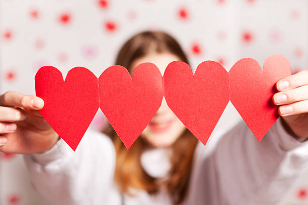 A young girl holding a string of paper hearts.