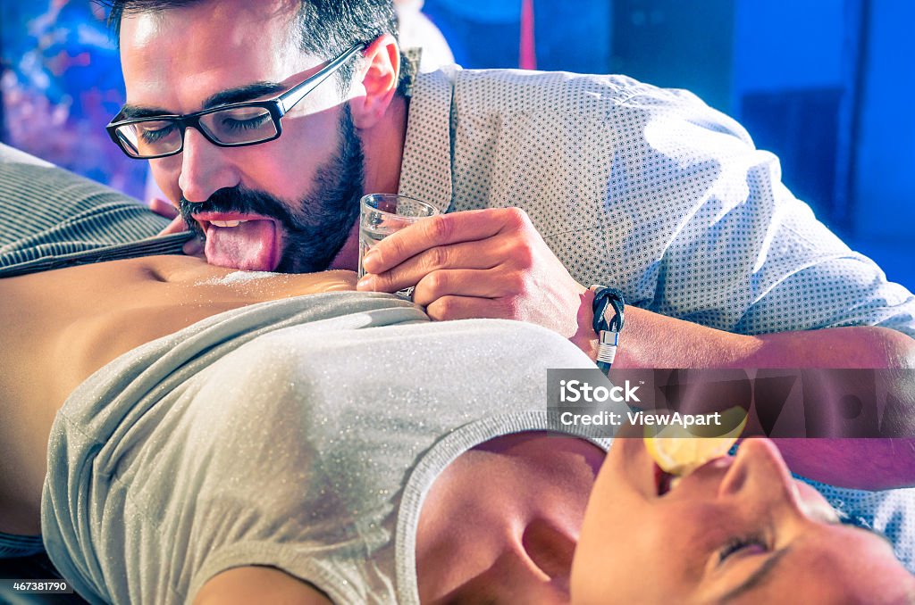 Couple having fun in disco nightclub with body tequila party Couple of friends having fun in disco night club with body tequila party - Nightlife with crazy drunk game for young people - Vintage look with soft focus on glass and salt with shallow depth of field Tequila - Drink Stock Photo