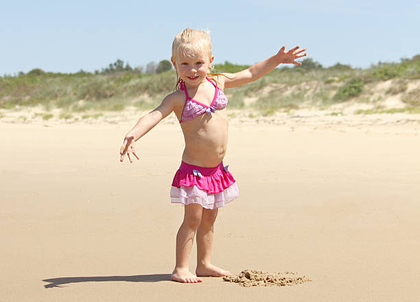 istock Litte girl playing in the sand at the beach 467382346