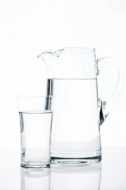 Water in a pitcher and water in a glass on white background