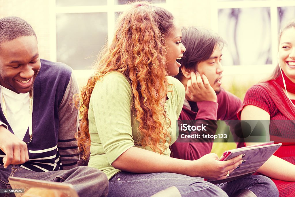 Education: Multi-ethnic group of college students hang out. Digital tablet. Multi-ethnic college friends hang out on campus.  Digital tablet. Cross processed. Outdoors Stock Photo