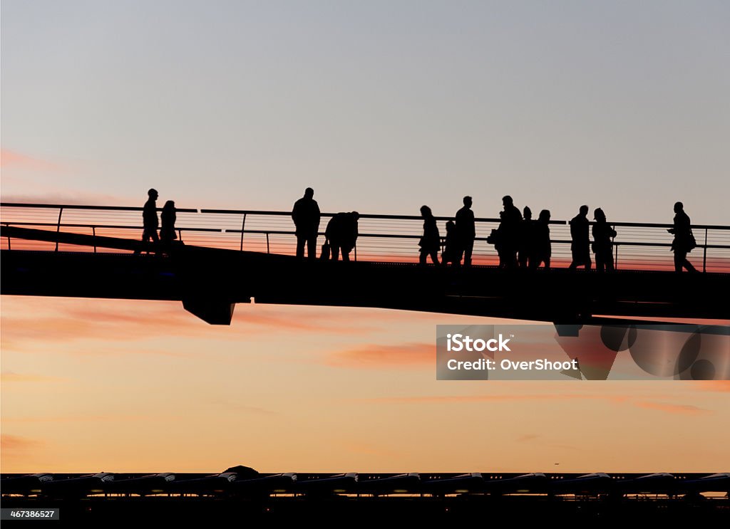 Walkers on the Millenium Bridge, London Walkers silhouetted on the Millenium Bridge, London, just after sunset. Side View Stock Photo