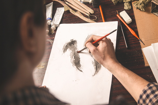 Young artist sketching a drawing with water colors. Unrecognizable person, male Caucasian.