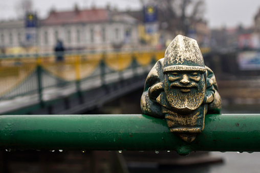 Little gnome statue on the bridge in the rain