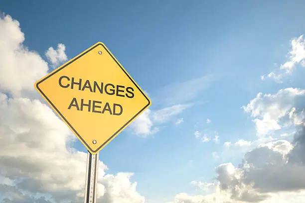 Photo of Yellow road sign saying changes ahead with blue cloudy sky