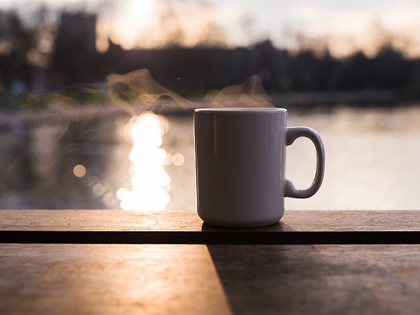 istock White mug sitting in front of sunlit lake 467398510