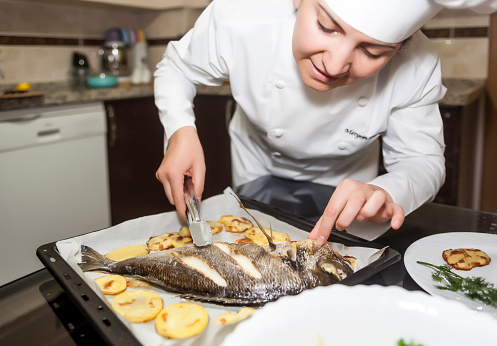 Female chef in kitchen preparing fish