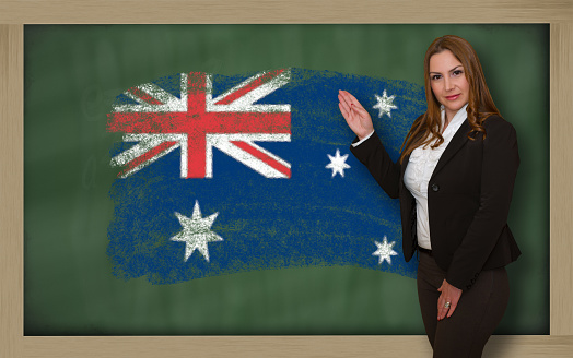 Successful, beautiful and confident woman showing flag of australia on blackboard for marketing research, presentation and tourist advertising